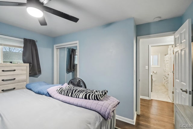bedroom with a ceiling fan, baseboards, dark wood finished floors, and a closet