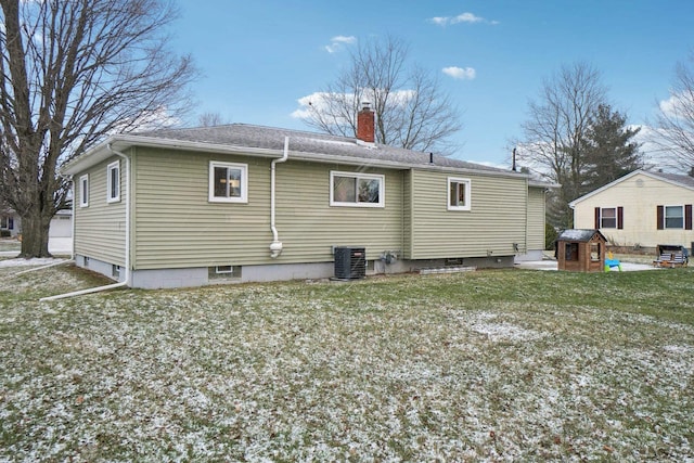 rear view of property with central air condition unit and a lawn