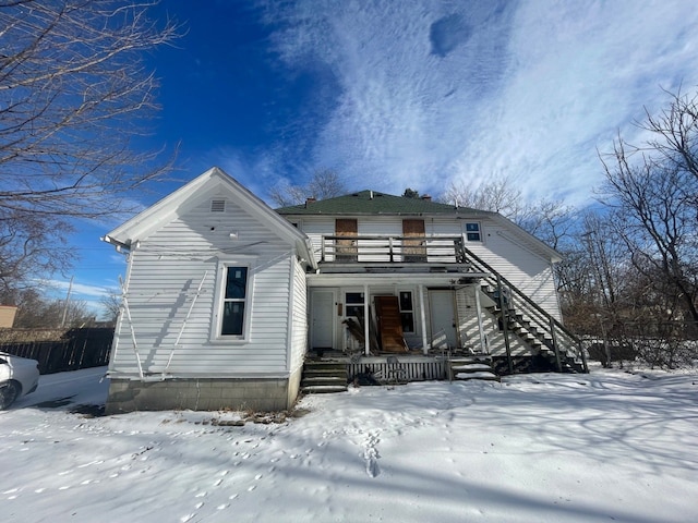 snow covered back of property with a balcony