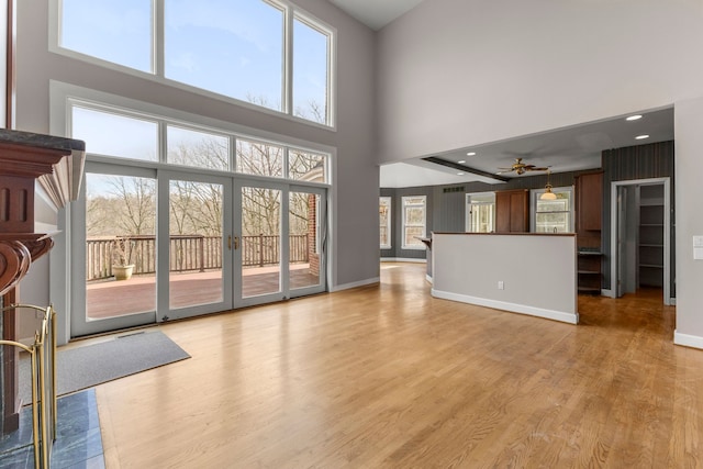 unfurnished living room featuring ceiling fan, a high ceiling, and a healthy amount of sunlight