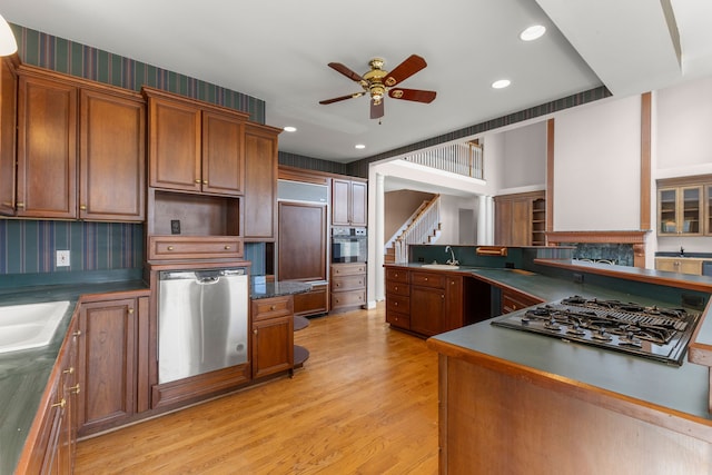 kitchen with ceiling fan, stainless steel appliances, backsplash, light wood-type flooring, and sink