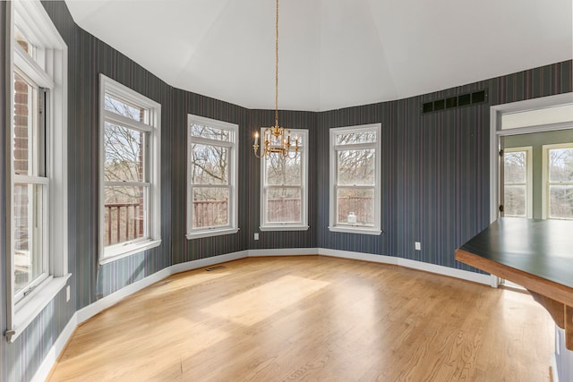 unfurnished dining area with a chandelier, lofted ceiling, and hardwood / wood-style floors