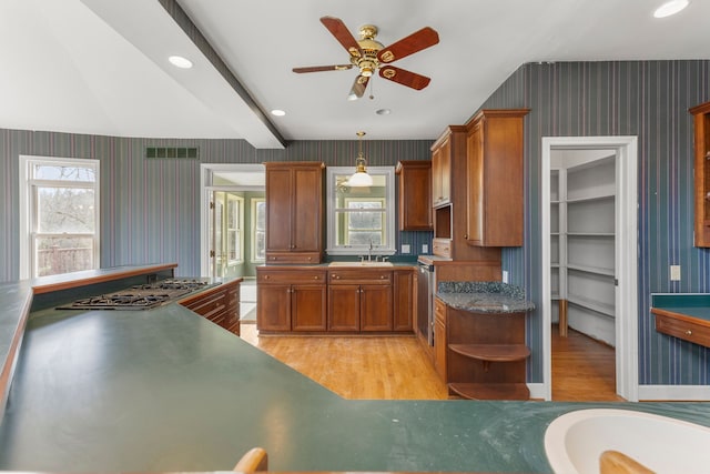 kitchen with pendant lighting, sink, stainless steel gas cooktop, ceiling fan, and light hardwood / wood-style flooring