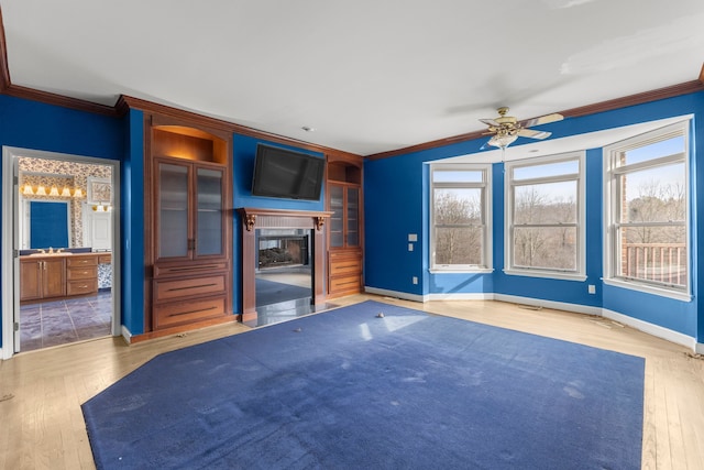 unfurnished living room featuring ceiling fan, crown molding, and light wood-type flooring