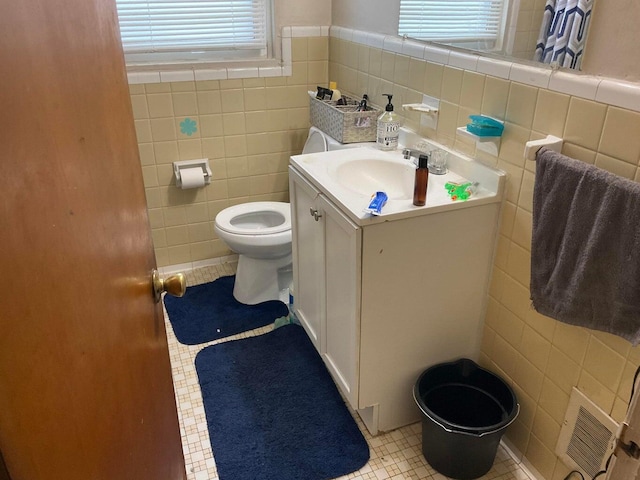 bathroom featuring tile patterned floors, vanity, toilet, and tile walls