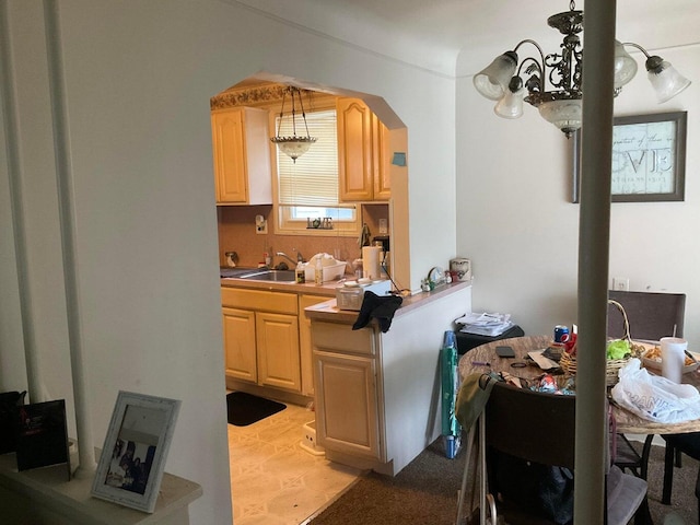 kitchen with light brown cabinetry, sink, light tile patterned floors, and decorative light fixtures