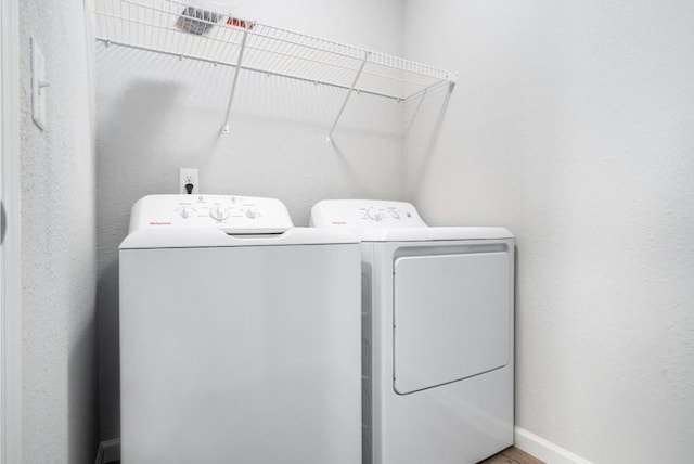 clothes washing area with washing machine and dryer and hardwood / wood-style floors