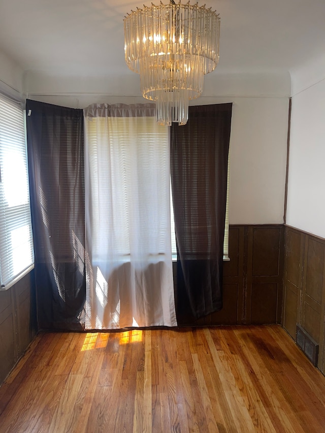 spare room with hardwood / wood-style floors and an inviting chandelier