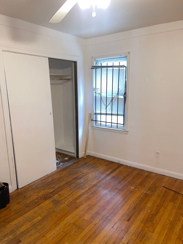 unfurnished bedroom with ceiling fan, a closet, and dark wood-type flooring