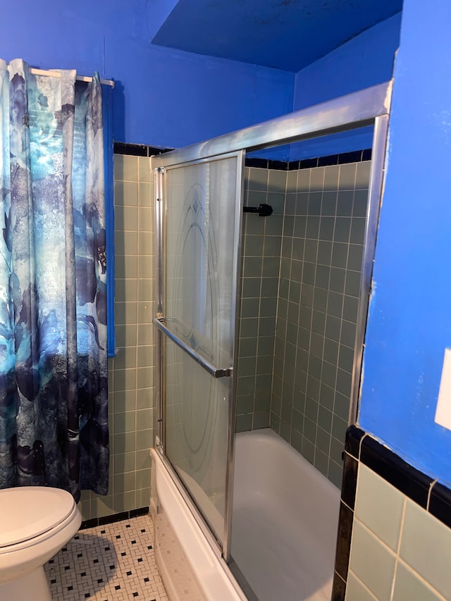 bathroom featuring tile patterned floors, bath / shower combo with glass door, and toilet