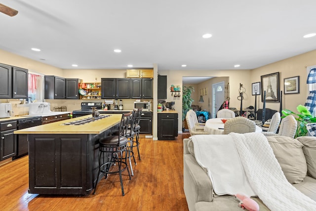 kitchen featuring a kitchen bar, a center island, light hardwood / wood-style flooring, and black appliances