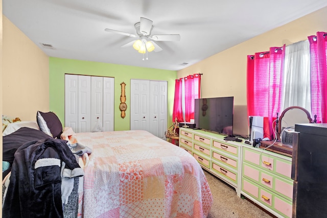 bedroom featuring ceiling fan, carpet floors, and two closets