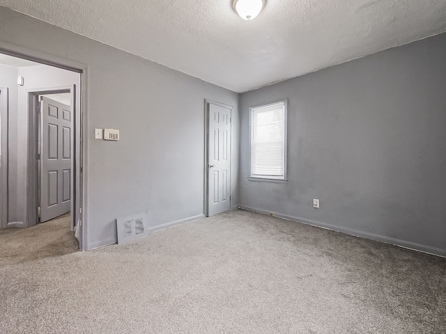 unfurnished bedroom with light carpet, a textured ceiling, and a closet