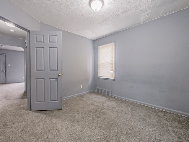 carpeted empty room with a textured ceiling