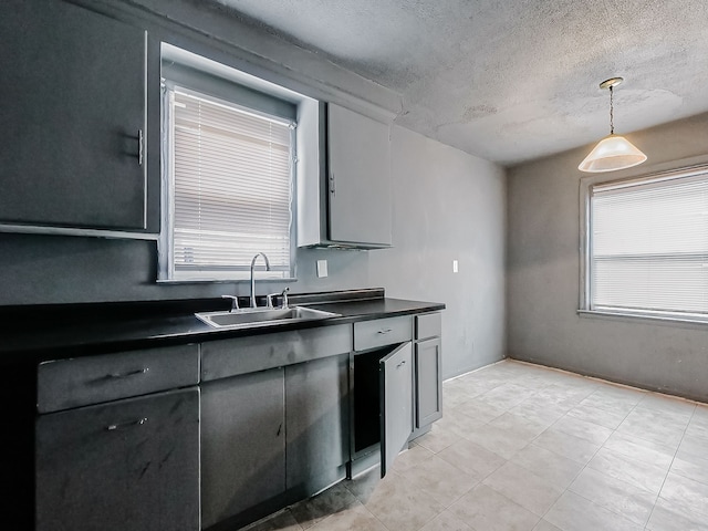 kitchen featuring a textured ceiling, sink, and hanging light fixtures