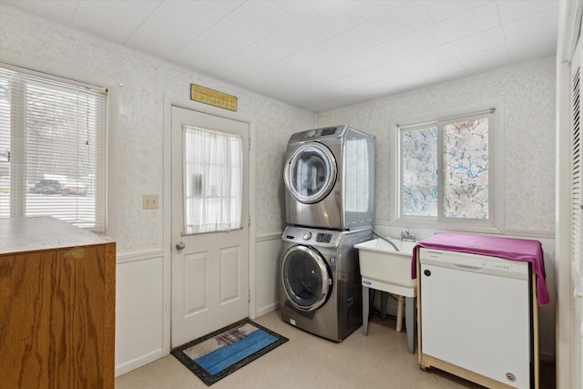 laundry area featuring stacked washing maching and dryer, sink, and a wealth of natural light