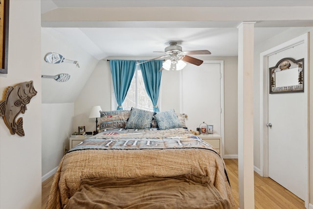 bedroom featuring ceiling fan, light hardwood / wood-style floors, and lofted ceiling