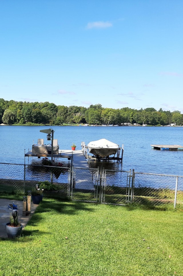 view of dock featuring a lawn and a water view