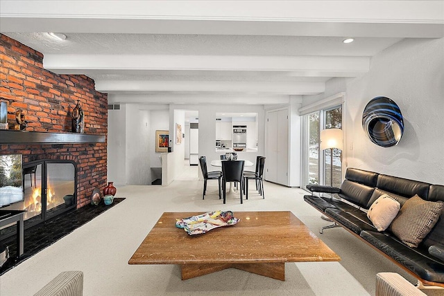 carpeted living room with a fireplace and beamed ceiling