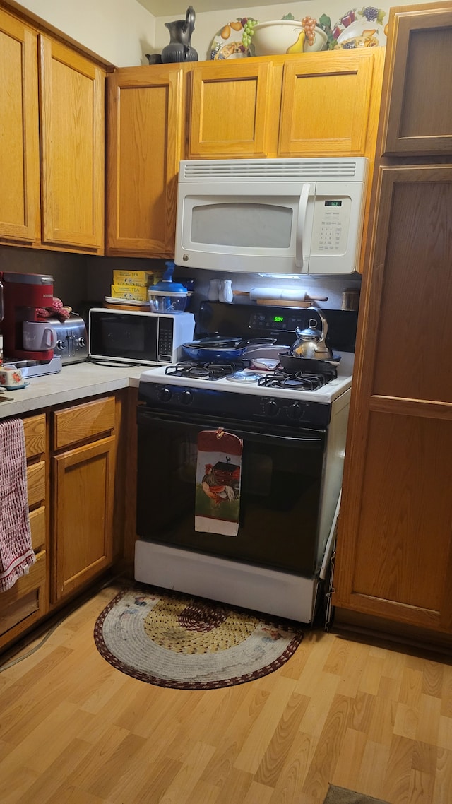 kitchen with white appliances and light hardwood / wood-style flooring