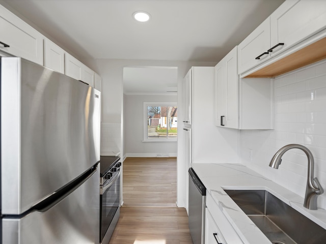 kitchen with light stone countertops, sink, stainless steel appliances, backsplash, and white cabinets