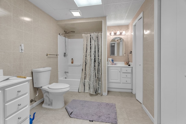 full bath featuring shower / tub combo with curtain, tile walls, toilet, vanity, and tile patterned floors