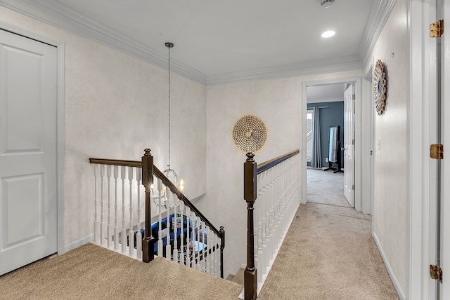 corridor featuring a chandelier, carpet floors, ornamental molding, and an upstairs landing