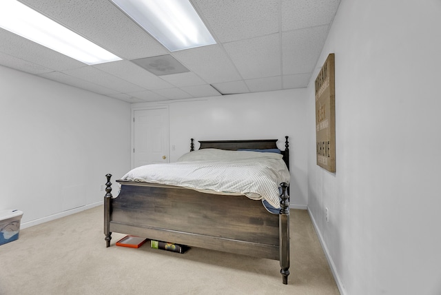 bedroom featuring a drop ceiling, carpet, and baseboards