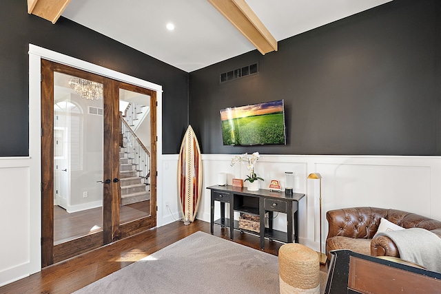 living area featuring dark hardwood / wood-style flooring, beamed ceiling, and an inviting chandelier