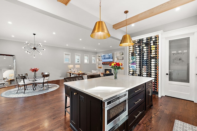 kitchen with a center island, dark wood-type flooring, a notable chandelier, pendant lighting, and a breakfast bar area