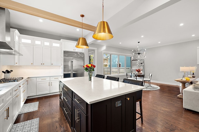 kitchen with white cabinets, wall chimney exhaust hood, stainless steel appliances, and decorative light fixtures