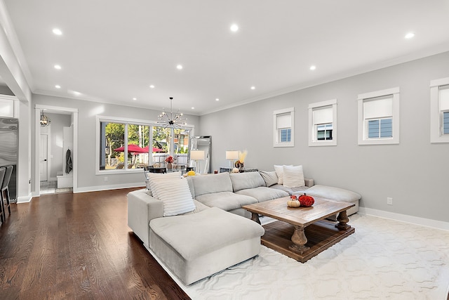 living room with wood-type flooring, ornamental molding, and an inviting chandelier