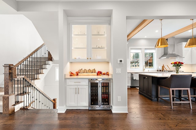 bar featuring white cabinetry, wall chimney exhaust hood, hanging light fixtures, beverage cooler, and stainless steel dishwasher