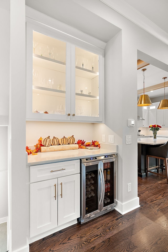 bar with white cabinetry, dark wood-type flooring, wine cooler, pendant lighting, and ornamental molding