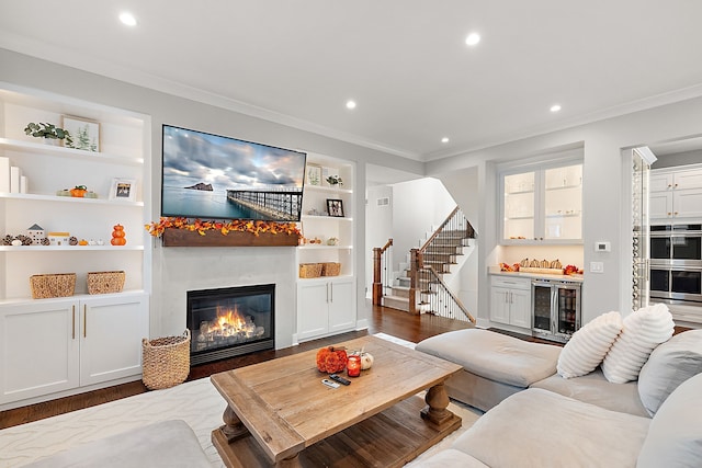 living room featuring built in shelves, indoor bar, beverage cooler, and wood-type flooring