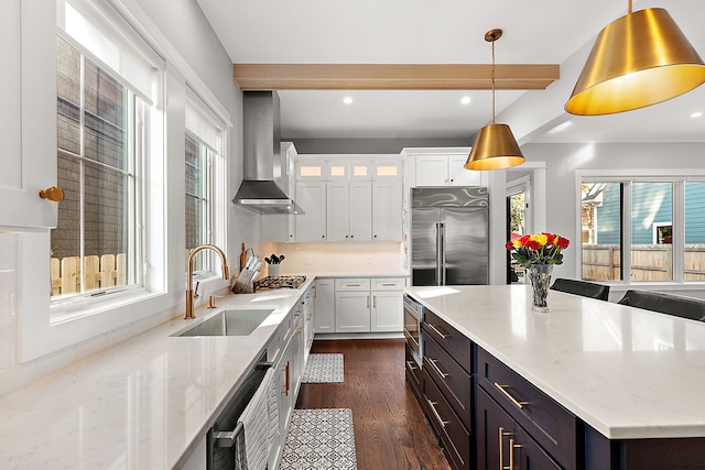 kitchen with wall chimney exhaust hood, stainless steel appliances, beam ceiling, decorative light fixtures, and white cabinets