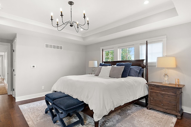 bedroom with dark hardwood / wood-style floors, a raised ceiling, ornamental molding, and an inviting chandelier