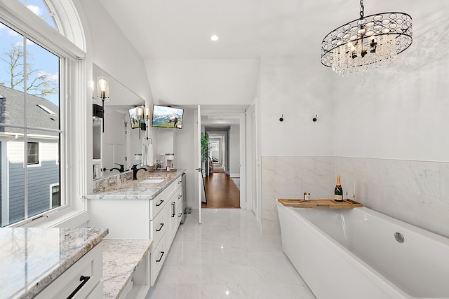 bathroom with a notable chandelier, vanity, a healthy amount of sunlight, and a washtub