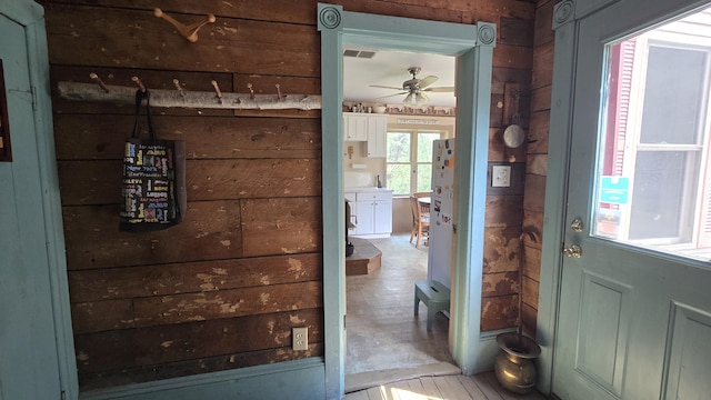 doorway to outside featuring wood walls and ceiling fan