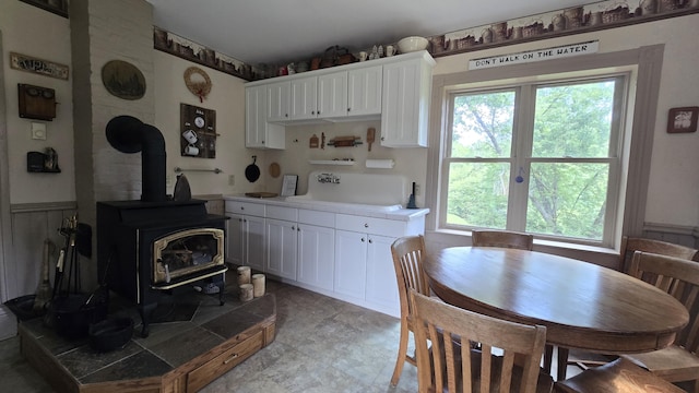 kitchen with white cabinets, a wood stove, and a healthy amount of sunlight