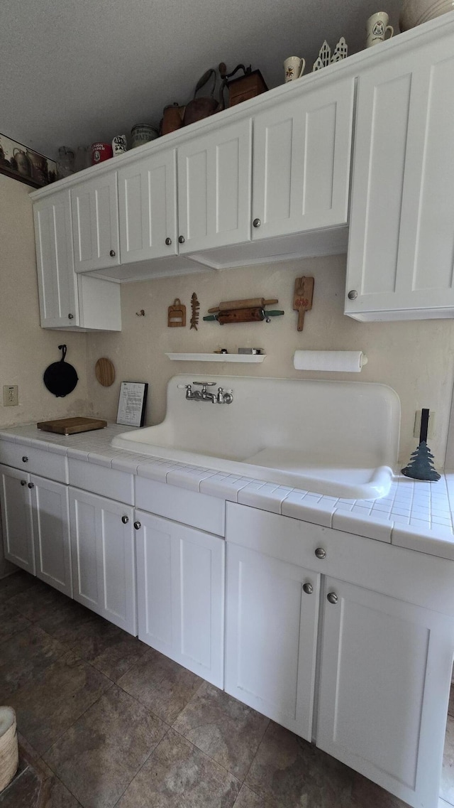 kitchen with white cabinetry and tile counters