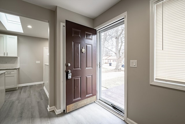 foyer entrance with a skylight and light wood-type flooring