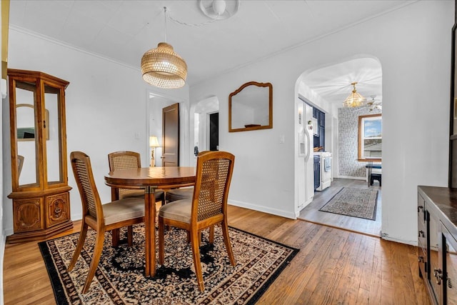 dining room featuring hardwood / wood-style flooring, brick wall, and a chandelier