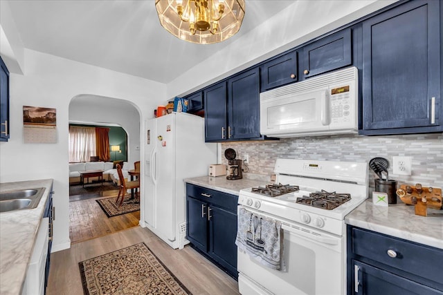 kitchen featuring blue cabinetry, light wood-type flooring, white appliances, and tasteful backsplash