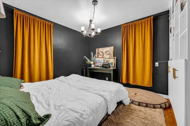 bedroom with hardwood / wood-style floors and an inviting chandelier