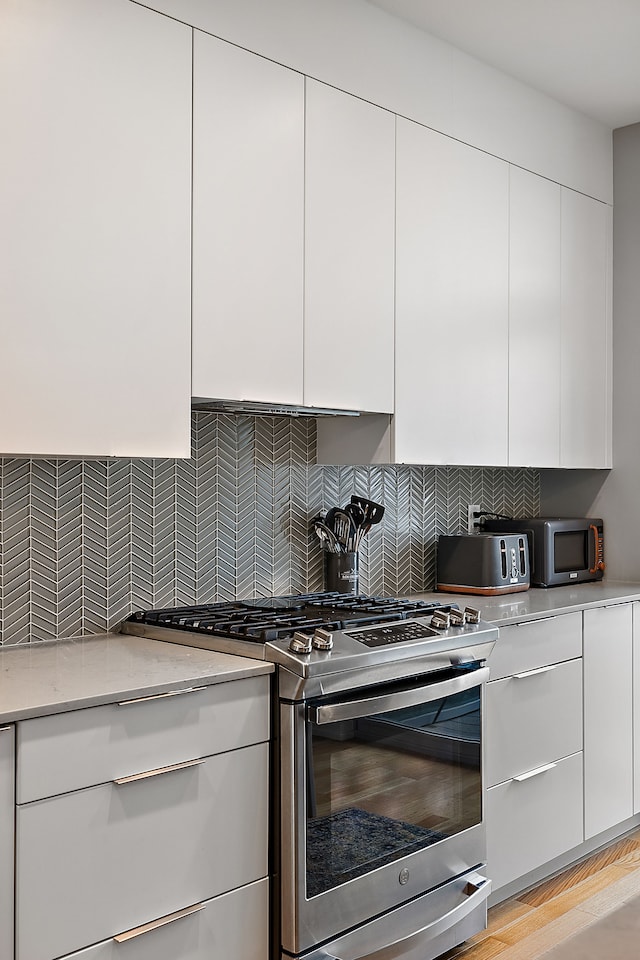 kitchen with appliances with stainless steel finishes, tasteful backsplash, white cabinetry, and light stone counters