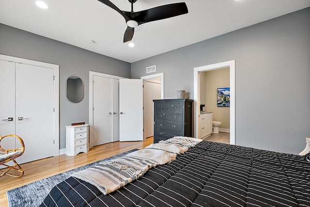 bedroom with hardwood / wood-style flooring, multiple closets, ceiling fan, and ensuite bathroom