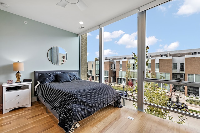 bedroom featuring light wood-type flooring and floor to ceiling windows