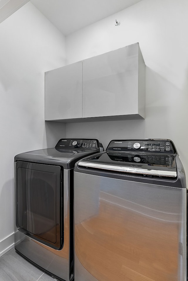 washroom with cabinets and washing machine and clothes dryer