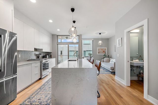 kitchen with appliances with stainless steel finishes, hanging light fixtures, white cabinets, backsplash, and sink